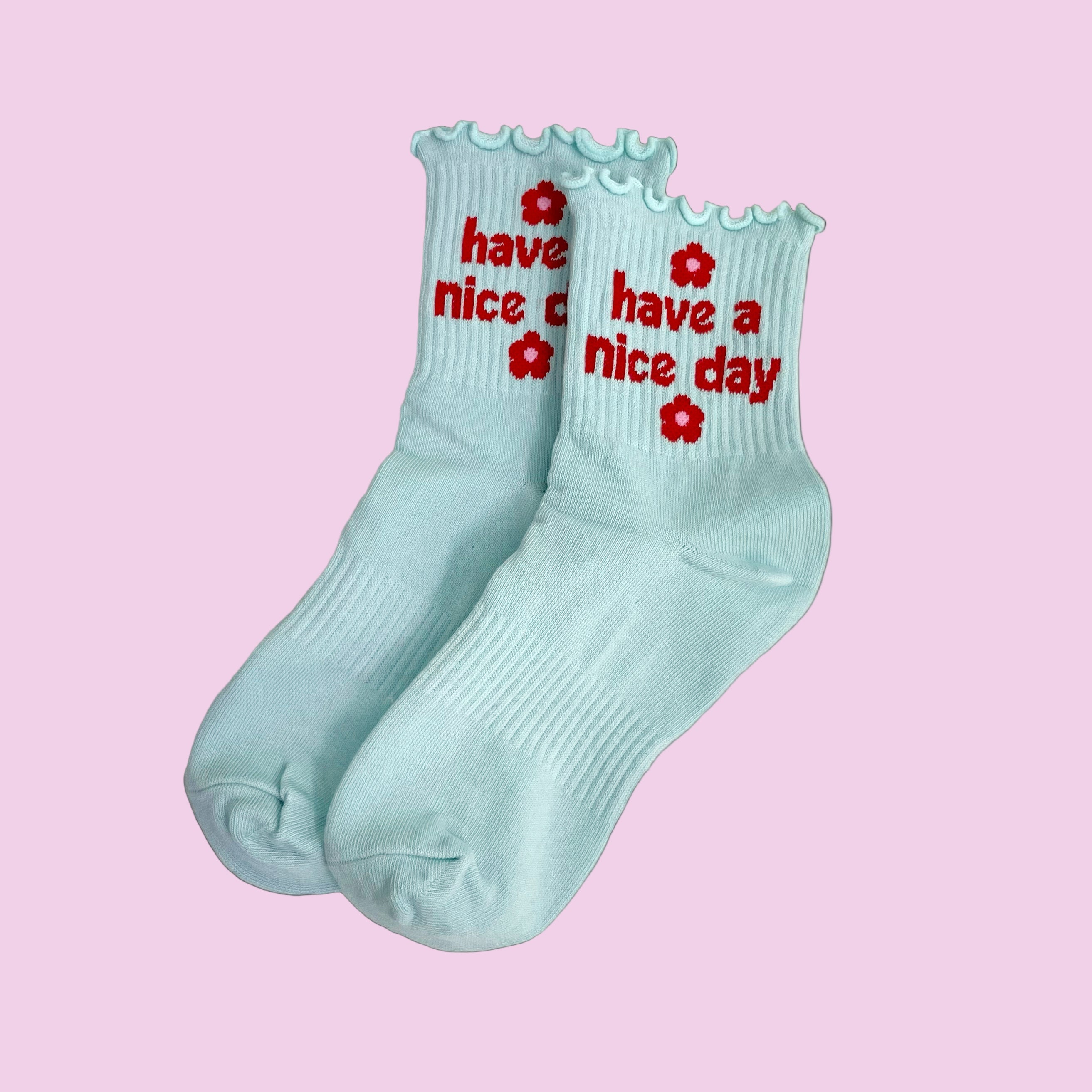 Light blue socks with red text and flowers on a pink background