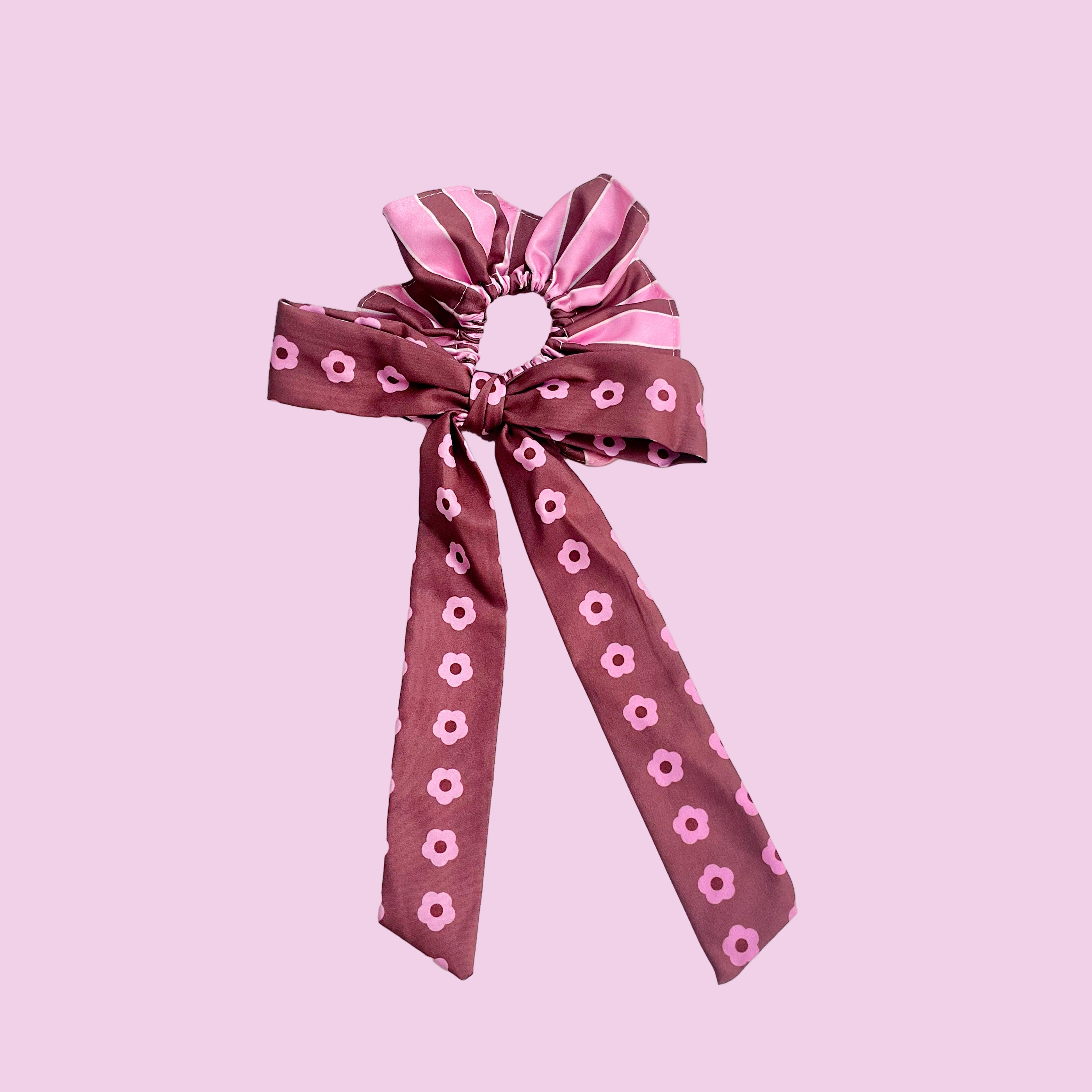 Pink scrunchie with a decorative ribbon on a pink background